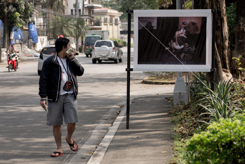 A man stares at a photo of a crime scene placed outside a church northwest of Manila. Photo: Eloisa Lopez.