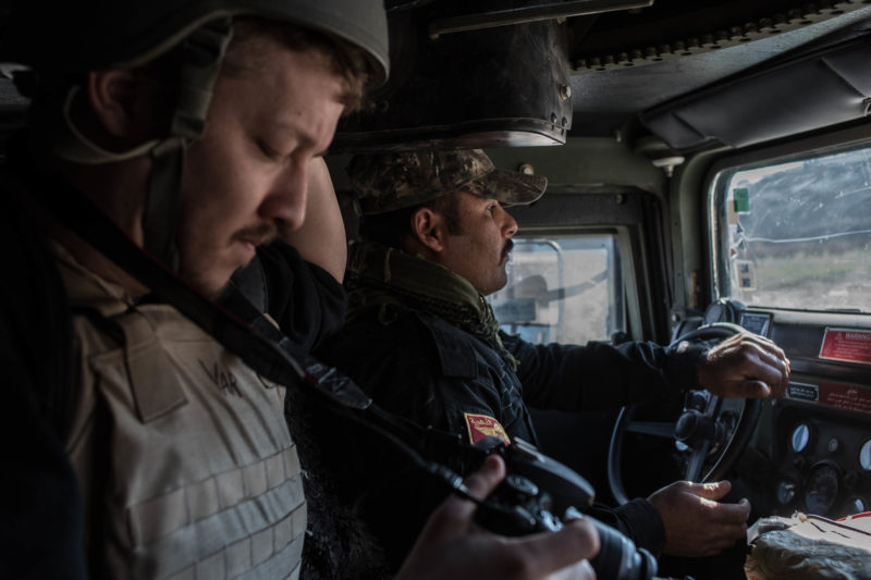 American freelance journalist Igor Kossov rides with an Iraqi special forces soldier in an armored vehicle in Mosul on January 17, 2017.