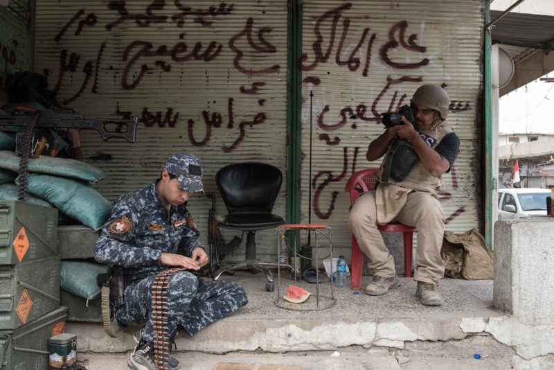 Brazillian freelance journalist Yan Boechat photographs an Iraqi federal policeman in west Mosul on May 6, 2017.